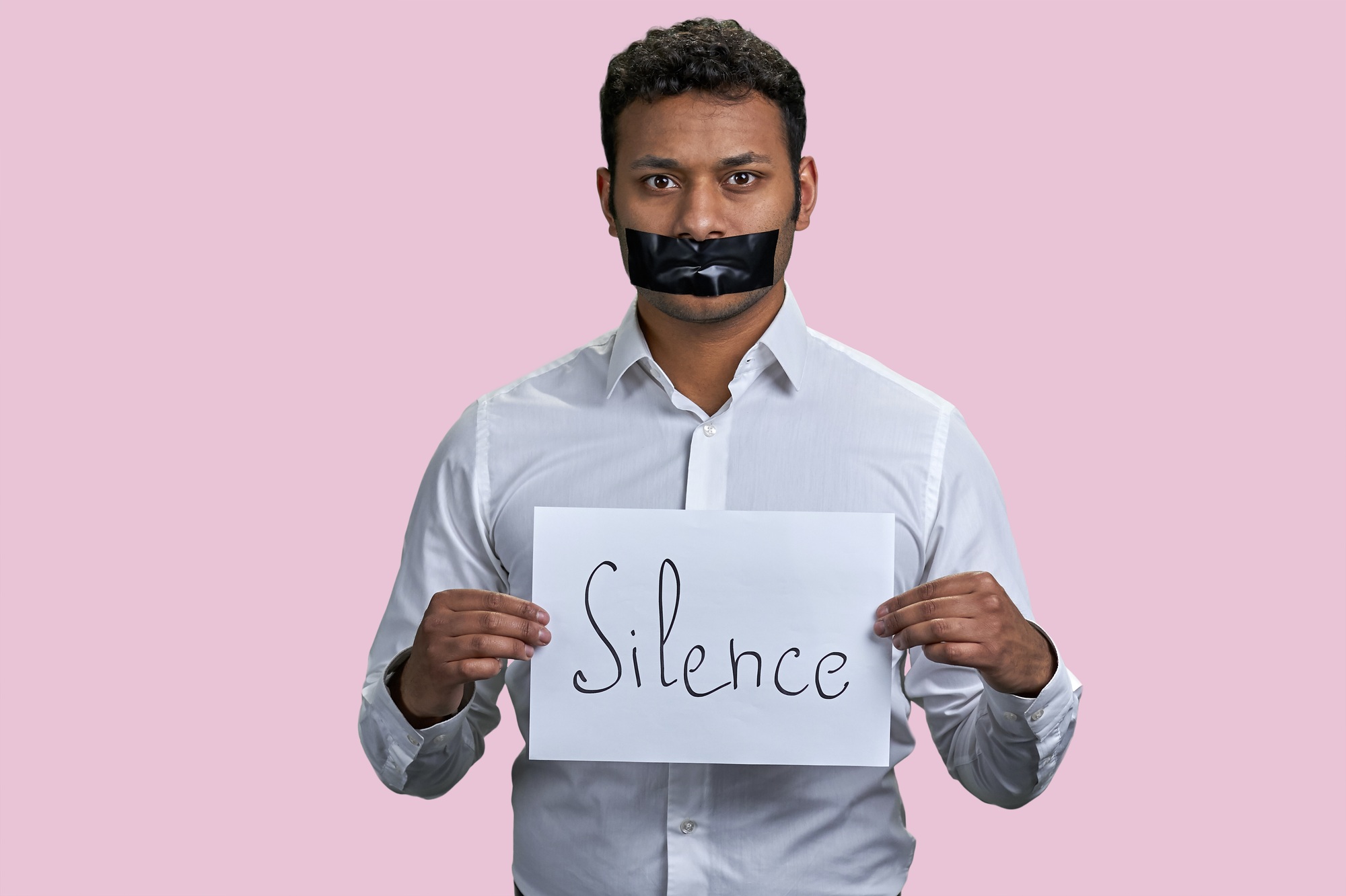 Brown indian man holding sheet of paper with silence word.