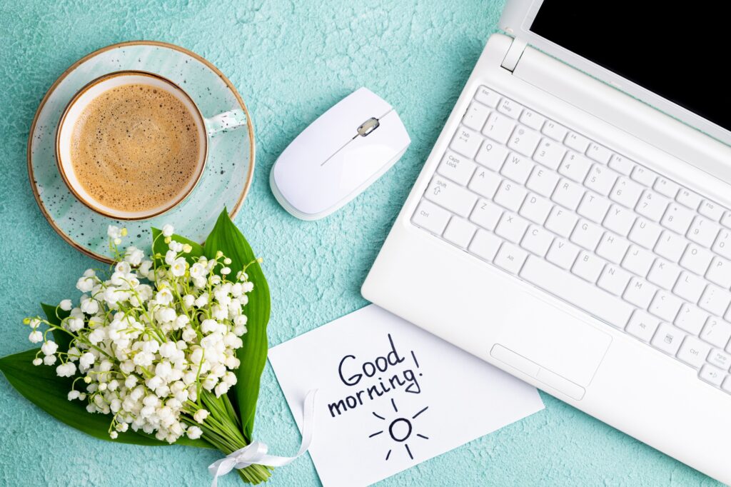 Home desk with notes good morning, coffee cup, bouquet of spring flowers lily of the valley