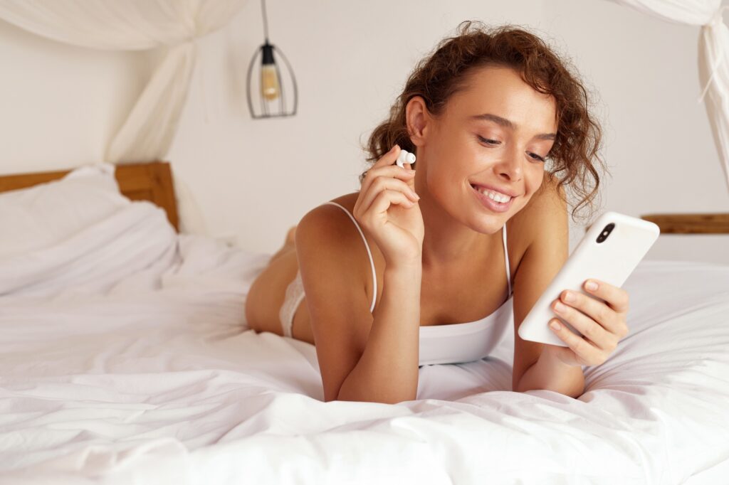 Woman Listening Music. Young Woman Using Smartphone And Earphones