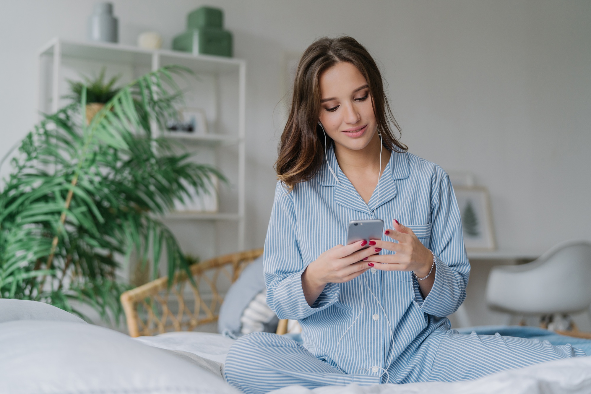 young European lady in pyjamas enjoys audio playlist, listens music romantic songs